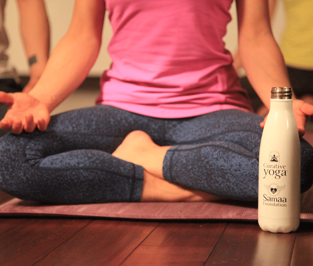 a person in a seated yoga pose with a water bottle in front of them